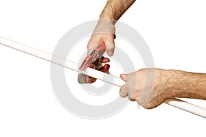 Hands worker cuts off a piece of polypropylene pipes. Isolated o