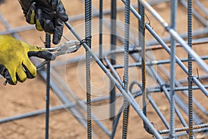 Hands of Worker Securing Steel Rebar Framing With Wire Plier Cutter Tool