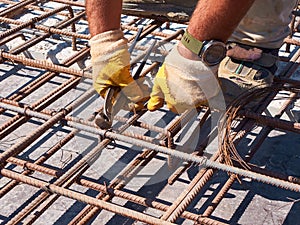 Hands of worker tying reinforcement rebars with haywire