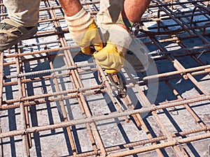 Hands of worker tying reinforcement rebars with haywire