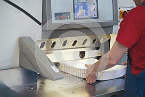 Hands of worker in typography working on cutter guillotine machine