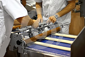 Hands of workers setting up equipment for the manufacture of confectionery and baking on the production line