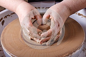 Hands working with clay on potter's wheel.
