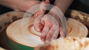 Hands working clay on potter`s wheel. Potter shapes the clay product with pottery tools on the potter`s wheel, craft factory authe