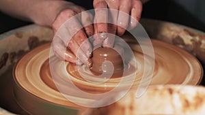 Hands working clay on potter`s wheel. Potter shapes the clay product with pottery tools on the potter`s wheel, craft factory authe