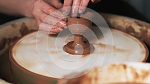 Hands working clay on potter`s wheel. Potter shapes the clay product with pottery tools on the potter`s wheel, craft factory authe