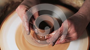 Hands working clay on potter`s wheel. Potter shapes the clay product with pottery tools on the potter`s wheel, craft factory authe