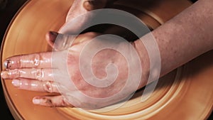 Hands working clay on potter`s wheel. Potter shapes the clay product with pottery tools on the potter`s wheel, craft factory authe