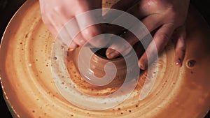 Hands working clay on potter`s wheel. Potter shapes the clay product with pottery tools on the potter`s wheel, craft factory authe