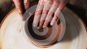 Hands working clay on potter`s wheel. Potter shapes the clay product with pottery tools on the potter`s wheel, craft factory authe