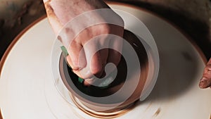 Hands working clay on potter`s wheel. Potter shapes the clay product with pottery tools on the potter`s wheel, craft factory authe