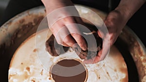 Hands working clay on potter`s wheel. Potter shapes the clay product with pottery tools on the potter`s wheel, craft factory authe