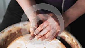 Hands working clay on potter`s wheel. Potter shapes the clay product with pottery tools on the potter`s wheel, craft factory authe