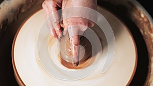 Hands working clay on potter`s wheel. Potter shapes the clay product with pottery tools on the potter`s wheel, craft factory authe