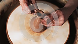 Hands working clay on potter`s wheel. Potter shapes the clay product with pottery tools on the potter`s wheel, craft factory authe