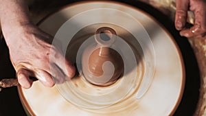 Hands working clay on potter`s wheel. Potter shapes the clay product with pottery tools on the potter`s wheel, craft factory authe