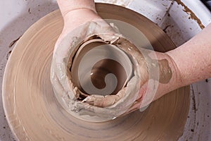 Hands working with clay on potter's wheel.