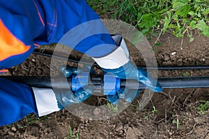 Hands working, close-up, checks the correct connection of the polypropylene pipe, to connect the water in the excavated trench