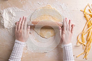 Hands working with dough for prepare fresh italian pasta. Female hands making dough for homemade pasta. Woman`s hands roll the