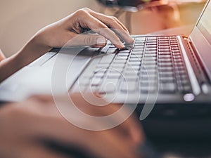 Hands working with keyboard on black laptop computer