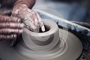 Hands working on pottery wheel , artistic toned photo