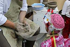 Hands working on pottery wheel and a little girl