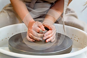 hands working and shaping ceramic on the lathe or potter's wheel inside a pottery workshop with natural ligh