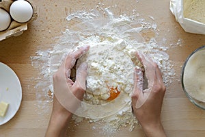 Hands working with shortbread dough. Preparation cake making from ingredients on wooden table background. Flat lay. Top view