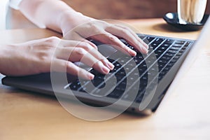 Hands working and typing on laptop keyboard in office