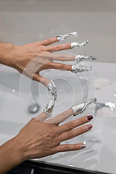 Hands wrapped in aluminum foil with acetone to remove traces of nail paint