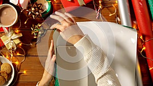 Hands wrapping christmas gift into paper at home