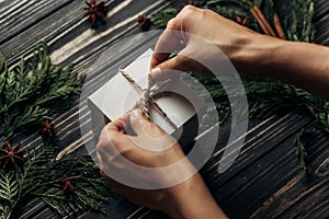 hands wrapping christmas simple present tying bow on stylish rustic wooden background with space for text. greeting card concept.