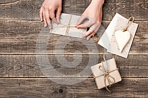 Hands wrapping craft paper envelope and gift box for present