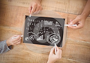 Hands writing equations on blackboard