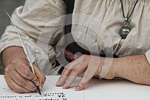 Hands writing a letter with a plume