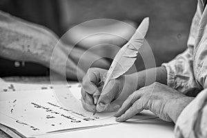 Hands writing a letter with a plume