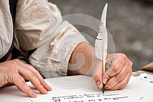 Hands writing a letter with a plume