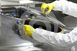 Hands in yellow gloves opening industrial process