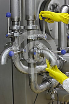 Hands in yellow gloves on tap and lever of technological system