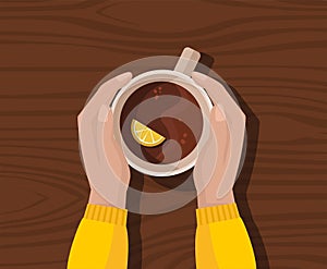 Hands in yellow sweater holding cup of tea with lemon.