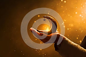 Hands of young asian muslim man hold shiny golden crescent moon with star lantern