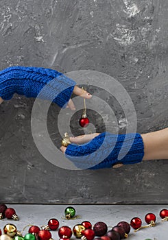 Hands of young beautiful woman in blue mittens. She holds a red ball in one hand and a yellow ball in the other. composition on a