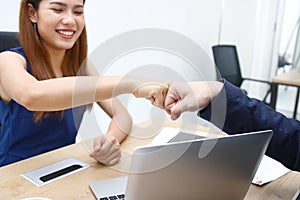 Hands of young business people giving fist bump together to greeting complete dealing in office. Success and teamwork concept