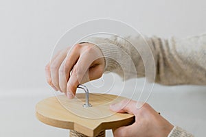 A young man is screwing a bolt into a board.