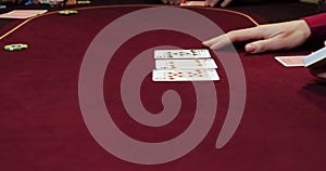 Hands of a young caucasian man playing poker in a casino. Close up of female hands with red cards.