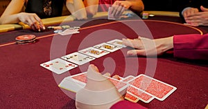 Hands of a young caucasian man playing poker in a casino. Close up of female hands with red cards.