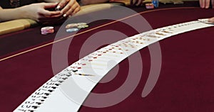 Hands of a young caucasian man playing poker in a casino. Close-up of hands playing poker with chips on red table.