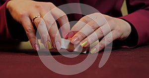 Hands of a young caucasian man playing poker in a casino. Close-up of hands playing poker with chips on red table.