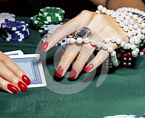Hands of young caucasian woman with red manicure at casino table