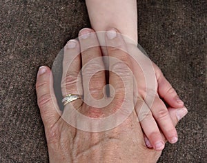 Hands of a young child and an old senior touching